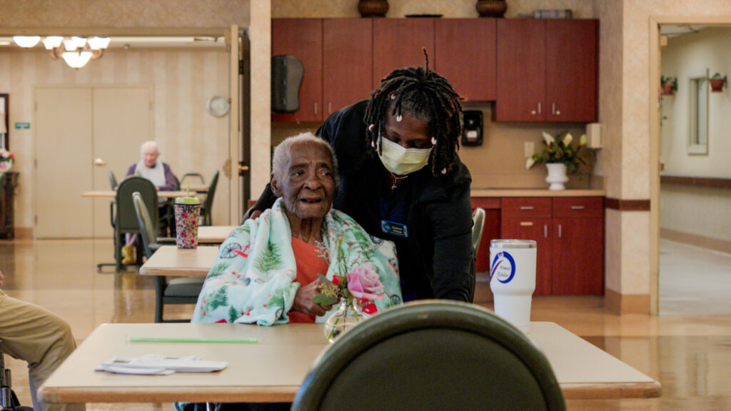 A nurse assists a woman in long term care