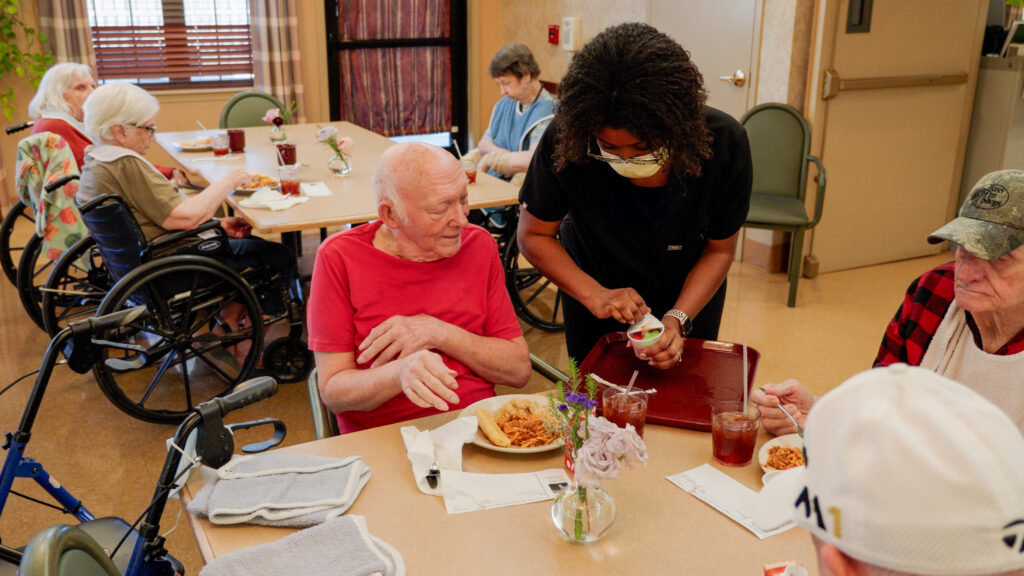 A nurse supplies a resident with dinner at a skilled nursing facility
