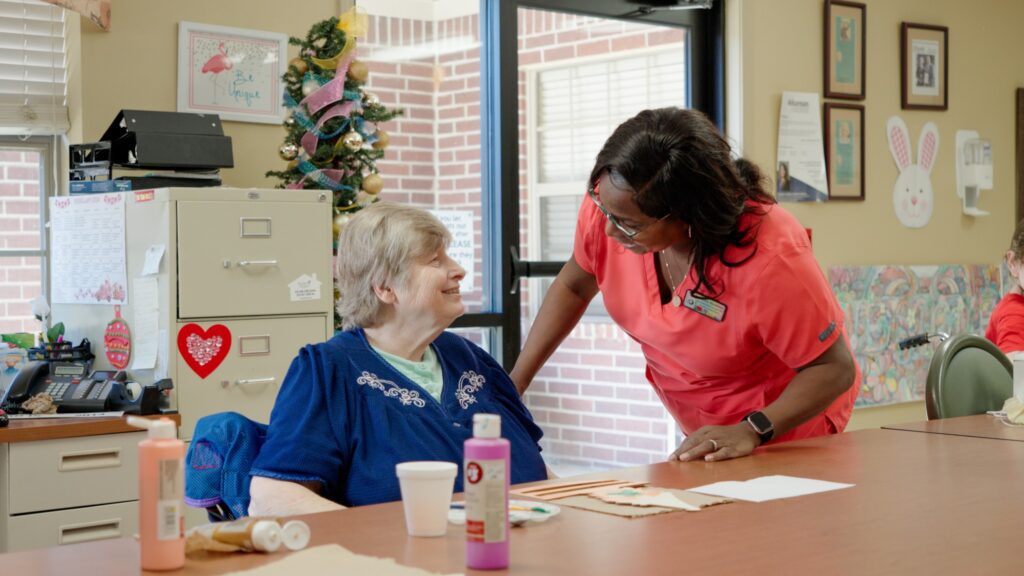 A nurse smiles at a long-term care resident of a skilled nursing facility